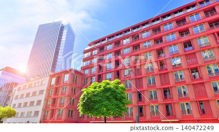 View of an modern apartment building standing next to a new modern office building with a glass facade. 140472249