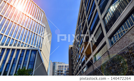 View of an modern apartment building standing next to a new modern office building with a glass facade. View of an modern apartment building standing next to a new modern office building with a glass facade. 140472264
