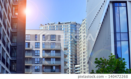 View of an modern apartment building standing next to a new modern office building with a glass facade. 140472268