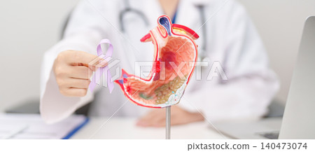 Doctor with Gastric anatomy model and Purple ribbon. November stomach cancer Awareness month, Gastroenterologist consultation, stomach diseases and ulcers, Gastroesophageal Reflux and Acid reflux 140473074