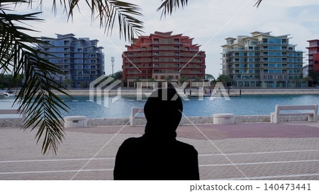 Woman overlooking waterfront residential buildings, tropical beach setting Woman overlooking waterfront residential buildings, tropical beach setting 140473441
