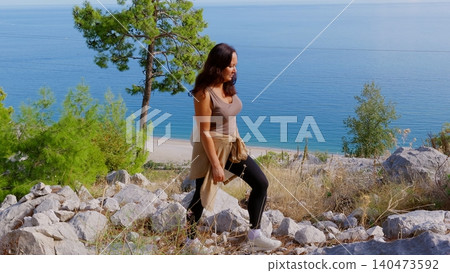 Woman hiking rocky coastal trail with sea view 140473592