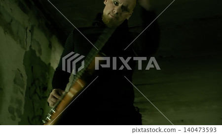 Musician holding bass guitar in abandoned warehouse setting 140473593