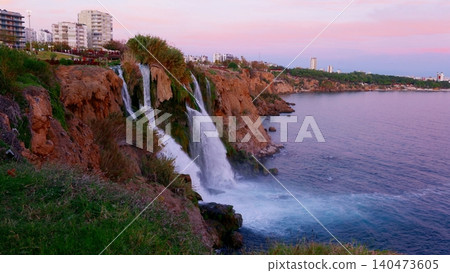 Waterfalls cascading from red cliff into Mediterranean sea at twilight Waterfalls cascading from red cliff into Mediterranean sea at twilight 140473605
