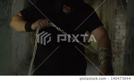 Man holding heavy metal chain in dark urban setting 140473644