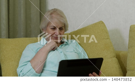 Senior woman using tablet computer on comfortable sofa Senior woman using tablet computer on comfortable sofa 140473852