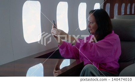 Woman taking selfie on airplane during flight Woman taking selfie on airplane during flight 140474010