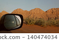 Car window mirror reflecting desert mountain landscape during road trip 140474034