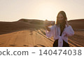 Woman taking selfie in desert while adjusting hair at sunset 140474038