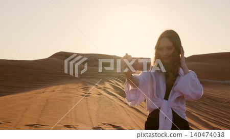 Woman taking selfie in desert while adjusting hair at sunset 140474038