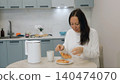 Woman breaking hot croissant at kitchen table with coffee 140474070