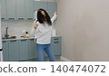Woman dancing, celebrating in modern kitchen with blue cabinets 140474072