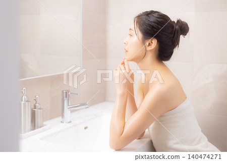A woman doing body care in the bathroom. 140474271