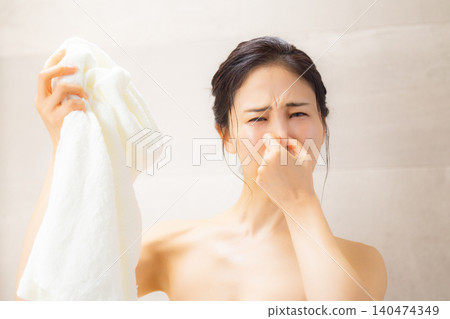 A woman sniffing a towel in the bathroom. A woman sniffing a towel in the bathroom. 140474349