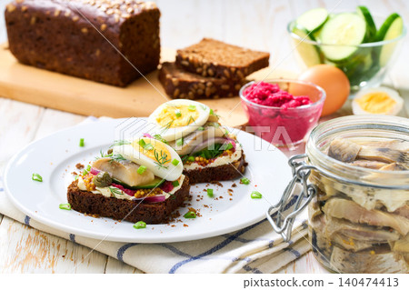 smorrebrod with rye toast bread and herring, boiling egg, red onions on wooden table, selective focus. smorrebrod with rye toast bread and herring, boiling egg, red onions on wooden table, selective focus. 140474413