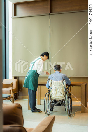 A man in a wheelchair and a female employee at a restaurant. A man in a wheelchair and a female employee at a restaurant. 140474436