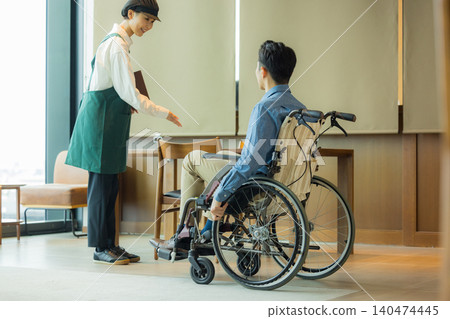 一名坐在輪椅上的男子和一名餐廳女員工。 一名坐在輪椅上的男子和一名餐廳女員工。 140474445