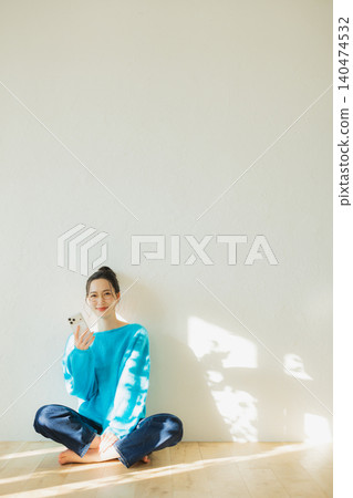 Young woman sitting on the floor and looking at smartphone 140474532