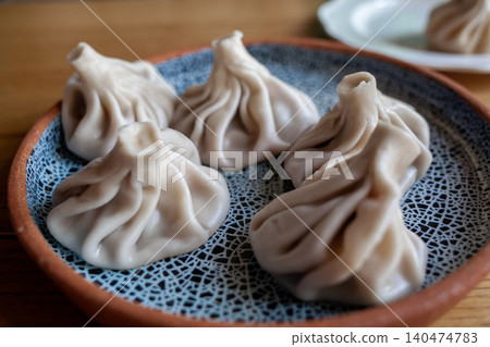 Savory dumplings arranged on a decorative plate showcase the culinary art of steaming in a friendly dining atmosphere at midday. Savory dumplings arranged on a decorative plate showcase the culinary art of steaming in a friendly dining atmosphere at midday. 140474783