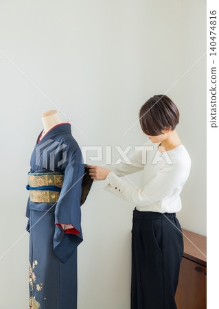A woman practicing how to put on a kimono on a mannequin. A woman practicing how to put on a kimono on a mannequin. 140474816
