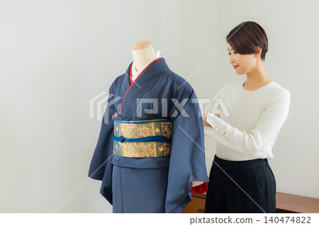 A woman practicing how to put on a kimono on a mannequin. A woman practicing how to put on a kimono on a mannequin. 140474822