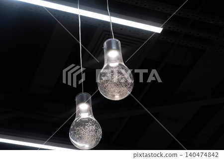 Two distinctive pendant lights hang from the ceiling, featuring transparent bulbs with intricate designs that add a stylish touch to the interior. 140474842