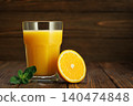 Orange juice in glass with mint and half citrus fruit on rustic wooden table 140474848