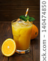 Fresh squeezed orange juice with ice and striped straw beside sliced ripe orange on dark wooden background 140474850