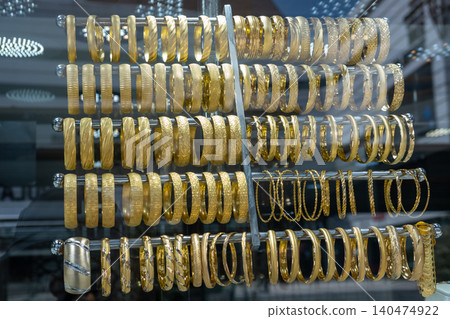 Rows of gold bangles are elegantly arranged in a jewelry store, highlighting intricate designs and craftsmanship, inviting customers to explore their choices. Rows of gold bangles are elegantly arranged in a jewelry store, highlighting intricate designs and craftsmanship, inviting customers to explore their choices. 140474922