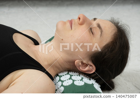 Relaxed Woman Using Acupressure Mat for Neck Pain Relief at Home Relaxed Woman Using Acupressure Mat for Neck Pain Relief at Home 140475007