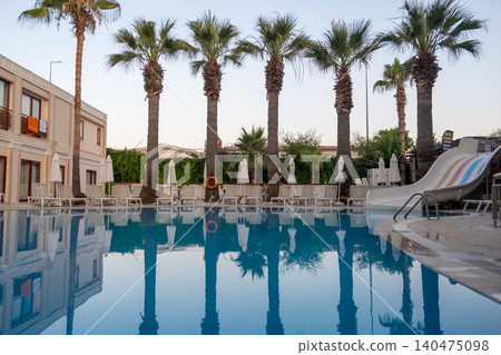 Luxurious hotel with swimming pool, palm trees, sun loungers and seating area. Palm trees are reflected in the clear water of the pool. Luxurious hotel with swimming pool, palm trees, sun loungers and seating area. Palm trees are reflected in the clear water of the pool. 140475098