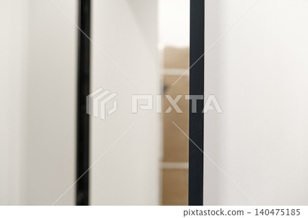 Door is being installed in a home renovation setting with plain walls and a glimpse of the unfinished space behind the door. Door is being installed in a home renovation setting with plain walls and a glimpse of the unfinished space behind the door. 140475185