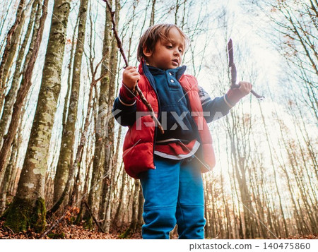 Child Exploring Forest with Sticks in Hand Child Exploring Forest with Sticks in Hand 140475860