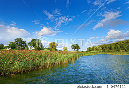 Nature, blue sky and lake with trees for environment, ecosystem and ecology outdoors. Natural background, landscape and aerial of water for scenic view, travel destination and terrain in countryside Nature, blue sky and lake with trees for environment, ecosystem and ecology outdoors. Natural background, landscape and aerial of water for scenic view, travel destination and terrain in countryside 140476111
