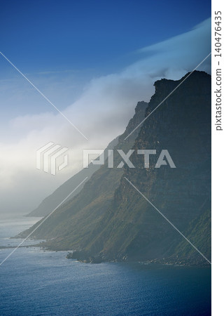 Mountain, clouds and natural island with ocean, blue sky and calm landscape for travel location. Nature, fog and sustainable environment with earth, sea and holiday destination with tropical summer Mountain, clouds and natural island with ocean, blue sky and calm landscape for travel location. Nature, fog and sustainable environment with earth, sea and holiday destination with tropical summer 140476435