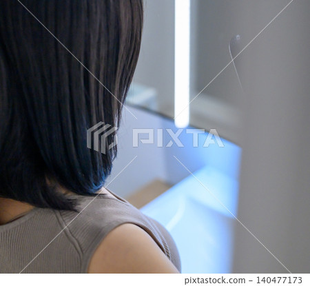 Back view of a woman in the mirror Back view of a woman in the mirror 140477173