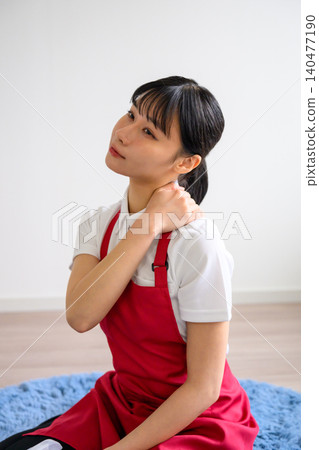 A woman in a red apron massaging her neck. A woman in a red apron massaging her neck. 140477190