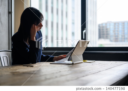 A woman struggling to decide what to do after reviewing the documents. A woman struggling to decide what to do after reviewing the documents. 140477198