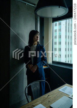Business woman standing by the window Business woman standing by the window 140477210