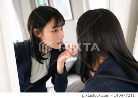 女人對著鏡子檢查自己的儀容。 140477211