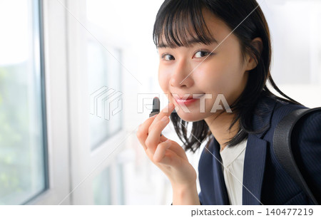 A woman applying makeup in front of a mirror A woman applying makeup in front of a mirror 140477219