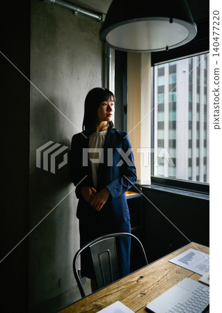 A woman in a suit looking out the window A woman in a suit looking out the window 140477220