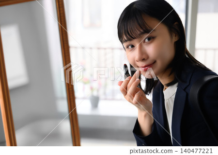 一位女士正在對著鏡子化妝。 140477221