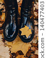 Close up view of boots standing on ground covered in yellow maple leaves. Stepping into autumn, seasonal transition concept, taking first step. 140477403