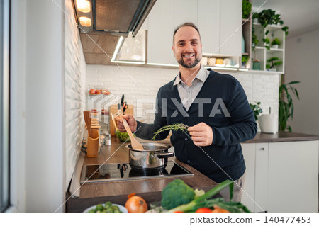 Mid adult man cooking healthy meal with fresh herbs Mid adult man cooking healthy meal with fresh herbs 140477453