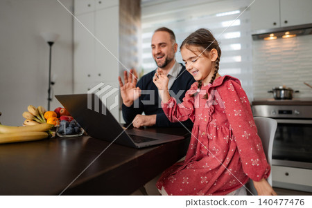 Father daughter laughing during video call on laptop 140477476