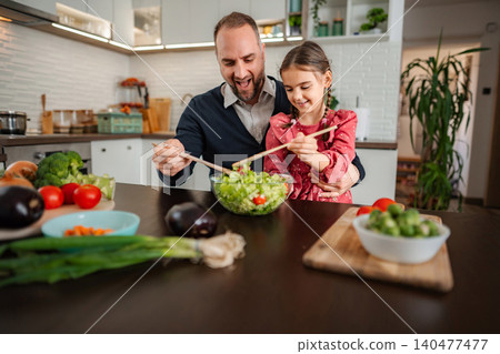 Father daughter mixing fresh salad for healthy meal 140477477