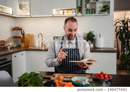 Man learning new recipe in kitchen with vegetables 140477493