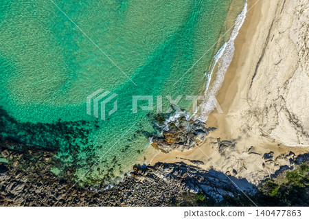 Aerial scene capturing the rocky shoreline of Charlotte Head meeting the sandy shore of Boomerang Beach near Pacific Palms, NSW, Australia.  140477863