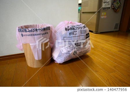 A trash can and a bag specifically for plastic waste placed near the kitchen. A trash can and a bag specifically for plastic waste placed near the kitchen. 140477956